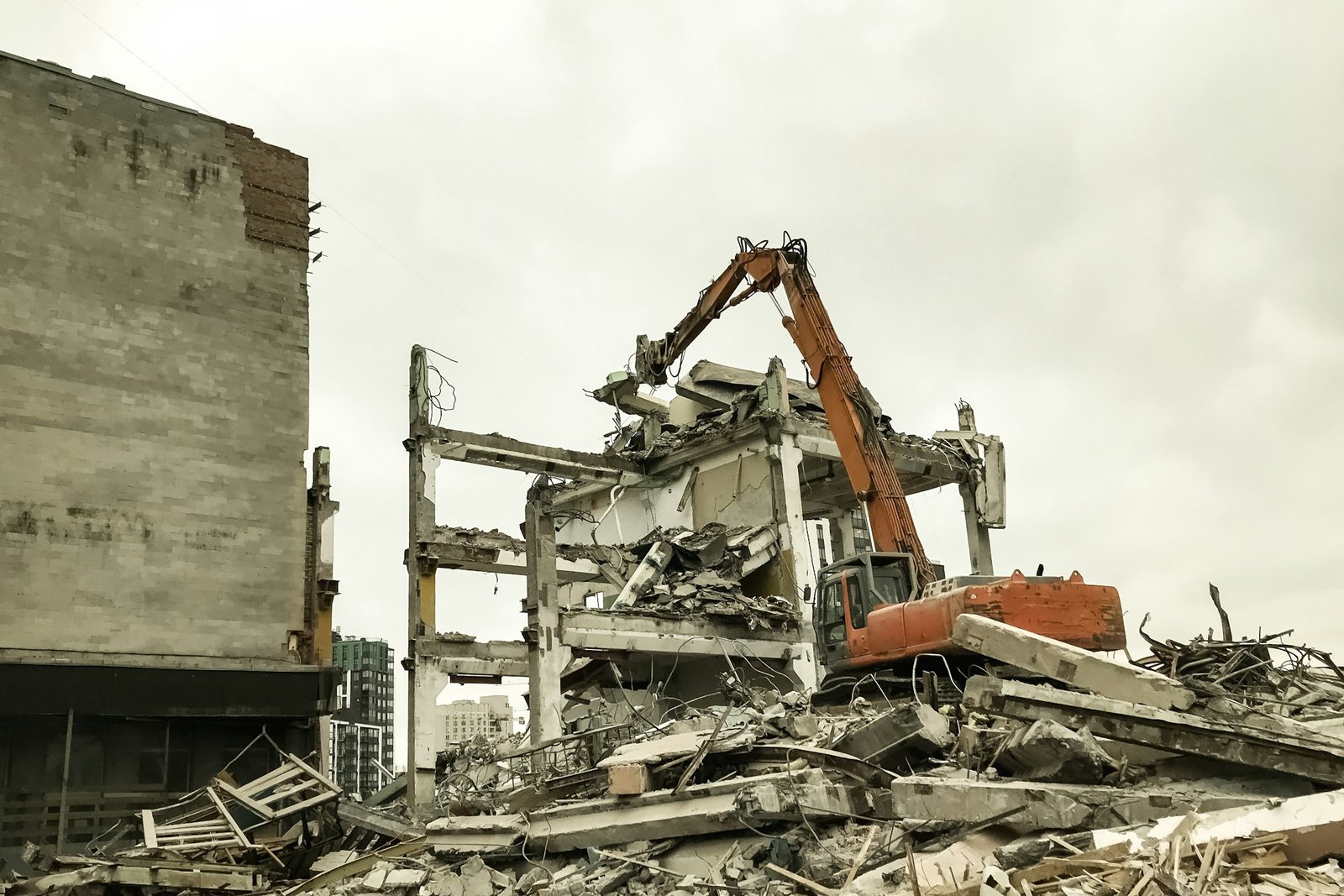 Hydraulic excavator demolition an old building at cloudy sky background